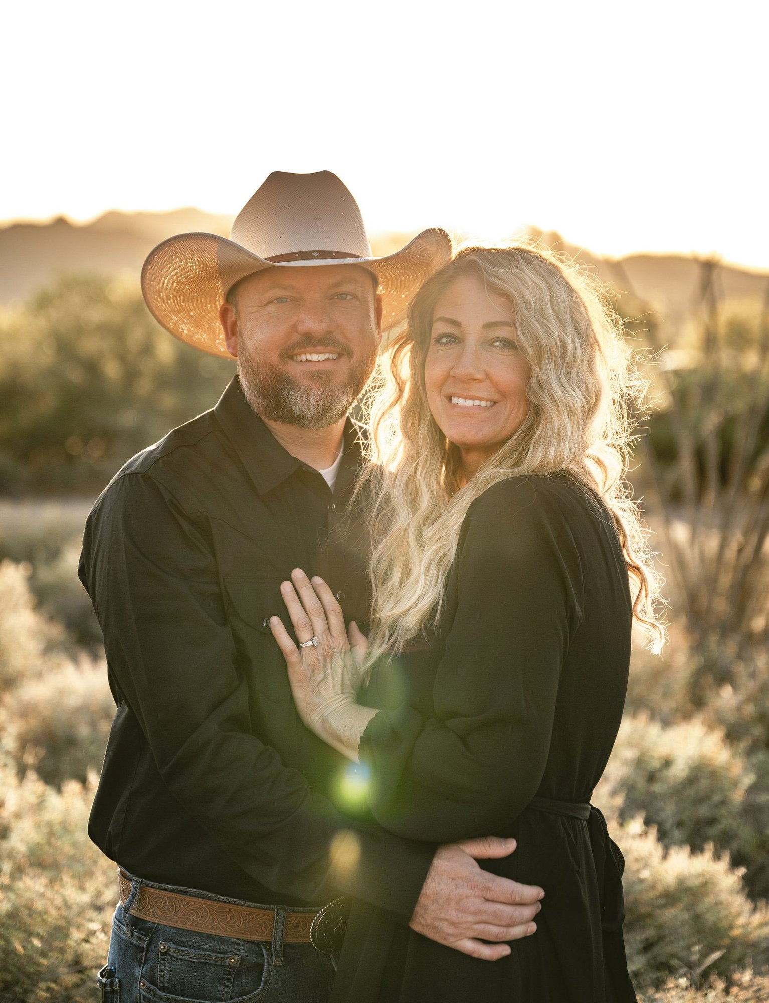 Couple in western attire with cowboy hat at golden hour