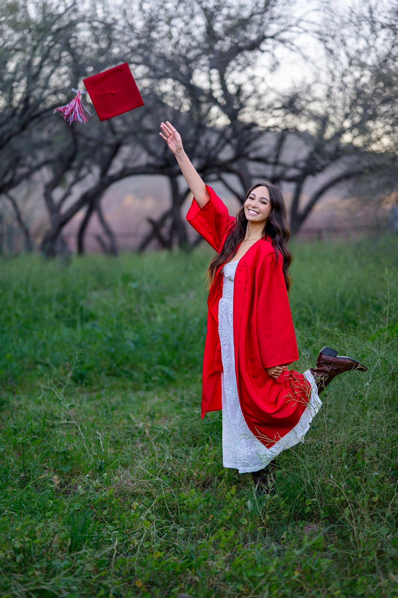 Senior girl throwing red graduation cap at Saguaro Lake